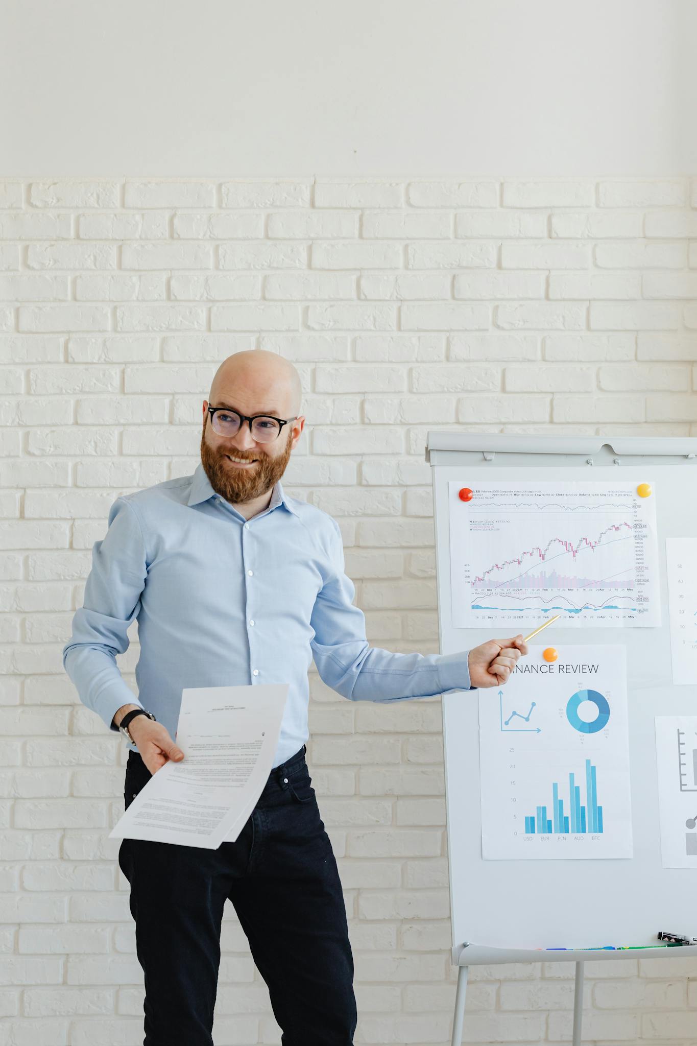 Smiling businessman with beard presenting financial charts at an office meeting.